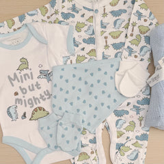 A baby clothing set ncluding a white short-sleeve bodysuit with dinosaur illustrations and the text 'Mini but Mighty,' a matching long-sleeve one-piece in blue-green and white with a dinosaur print, light blue bib with small blue dinosaur foot prints motifs, a white mittens and a folded blue knit blanket.